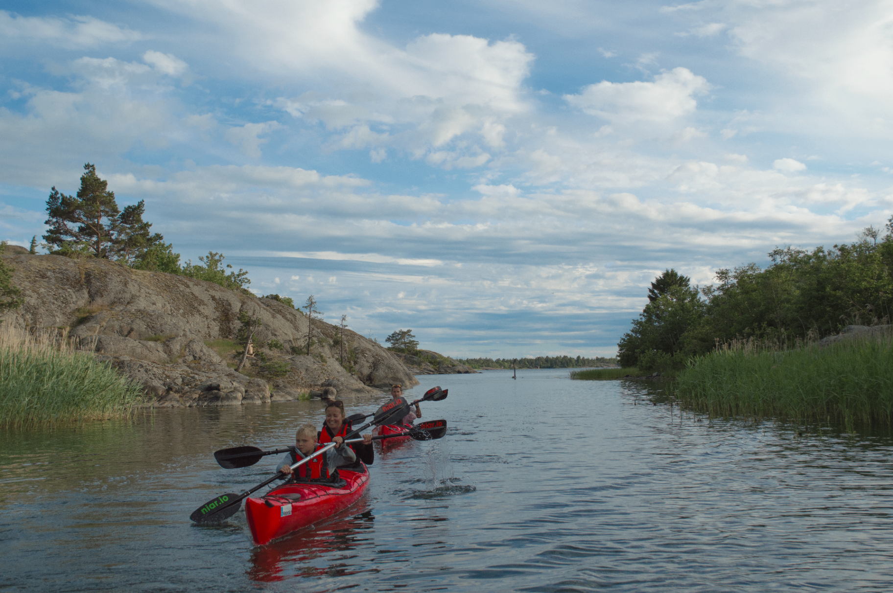 Kayakers on crystal-clear water in the Åland archipelago at sunset